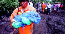 this fireman in Panabaj Guatemala is carrying in his arms a dead child one of many after the worst houricane to hit the region in 10 years.