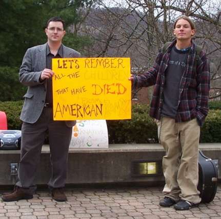 Micheal O Coileain stands along by Jarrod holding a poster asking people to think on all the children who have died from american bombs